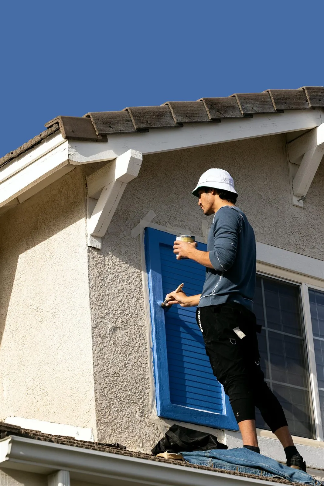 Painter working on blue exterior trim