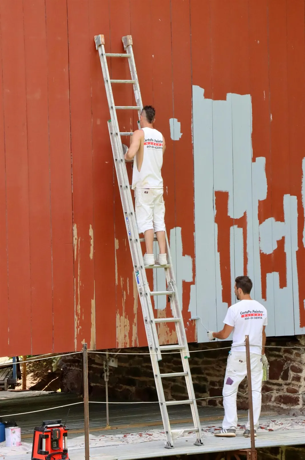 Painter working from a ladder on an exterior wall