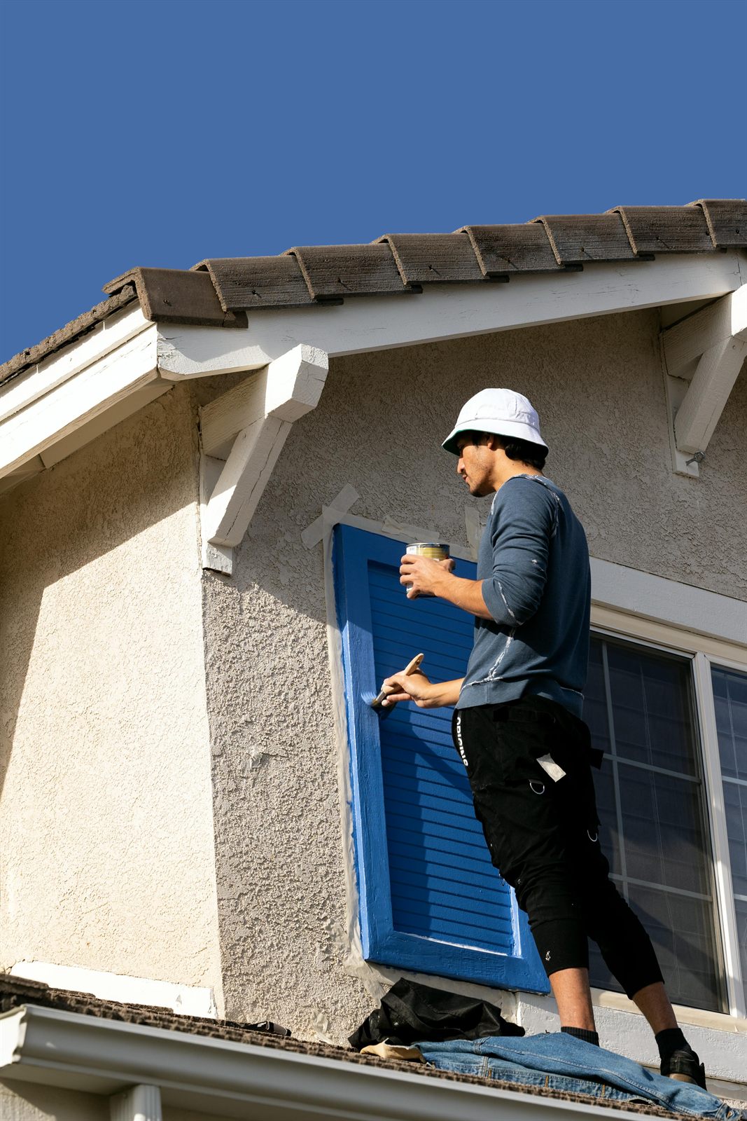 Painter applying blue exterior trim paint on a Hampton Roads home